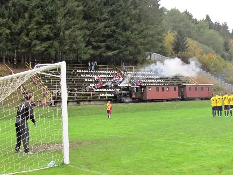 Vlak prechadza okolo ihriska pocas futbaloveho zapasu