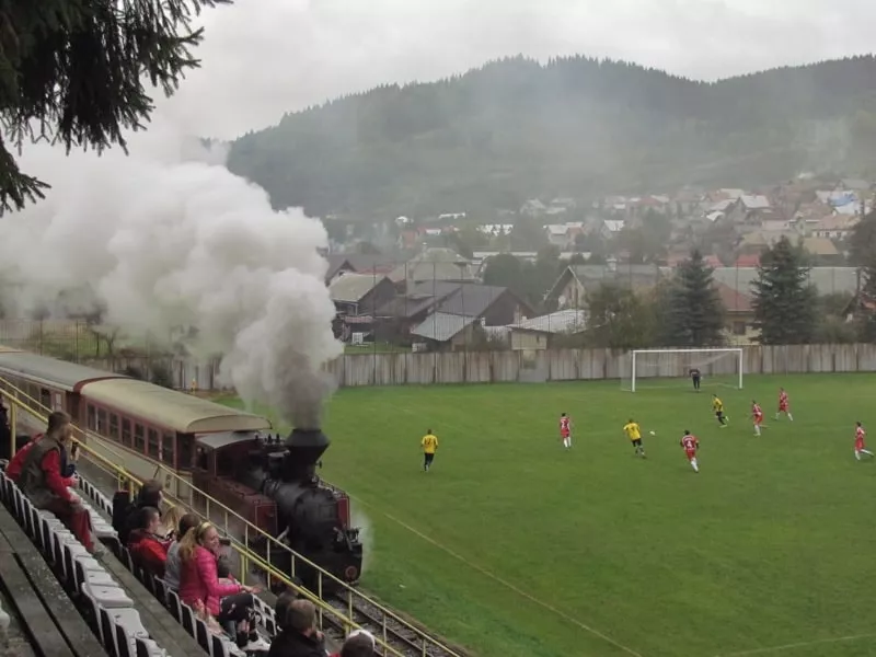 Vlak prechadza medzi futbalovym ihriskom a tribunou