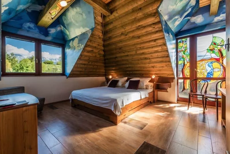 Izba s postelou v rohu, okna po bokoch a drevene oblozenie
