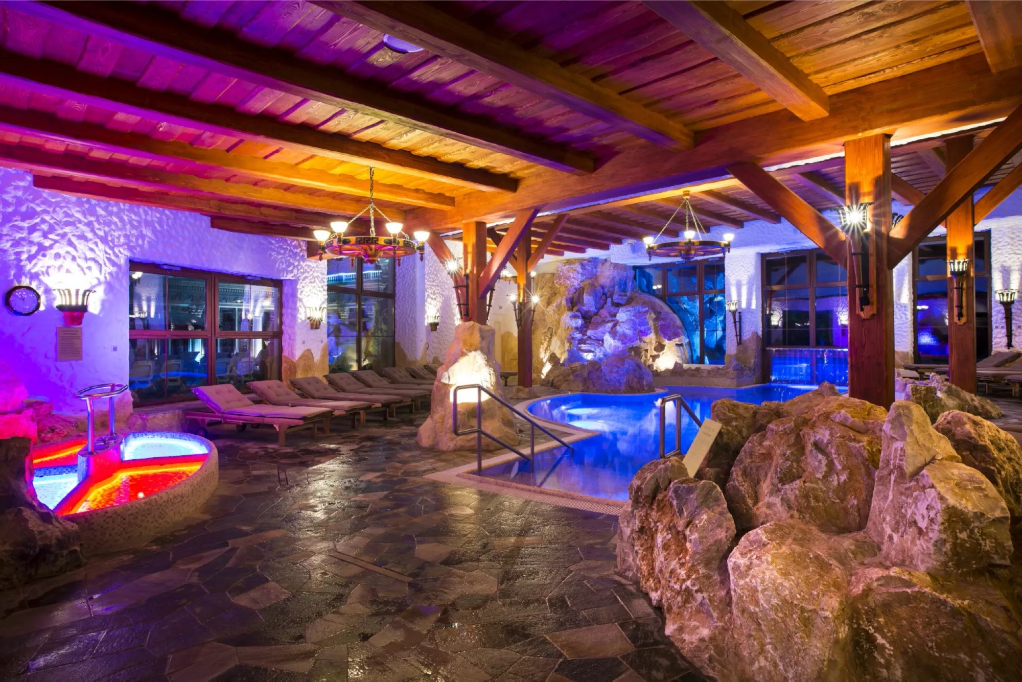 Interier saunoveho sveta. Vidno Kneippov kupel, vnutorny bazen s vychodom, lehatka, prijemne cerveno modre osvetlenie.