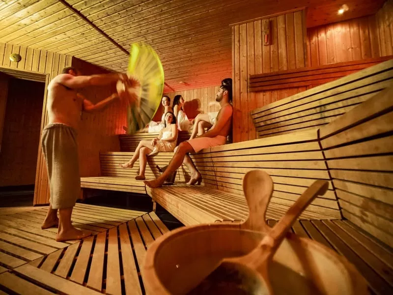 Skupinka ludi v saune s drevenym obkladom.