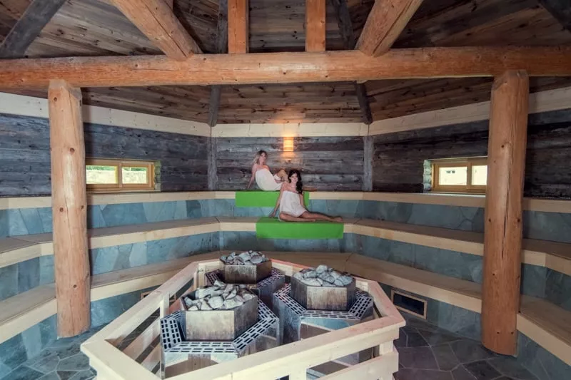 Dve zeny v Kelo saune kde sa kuri drevom. Cela miestnost posobi ako dreveny domcek.
