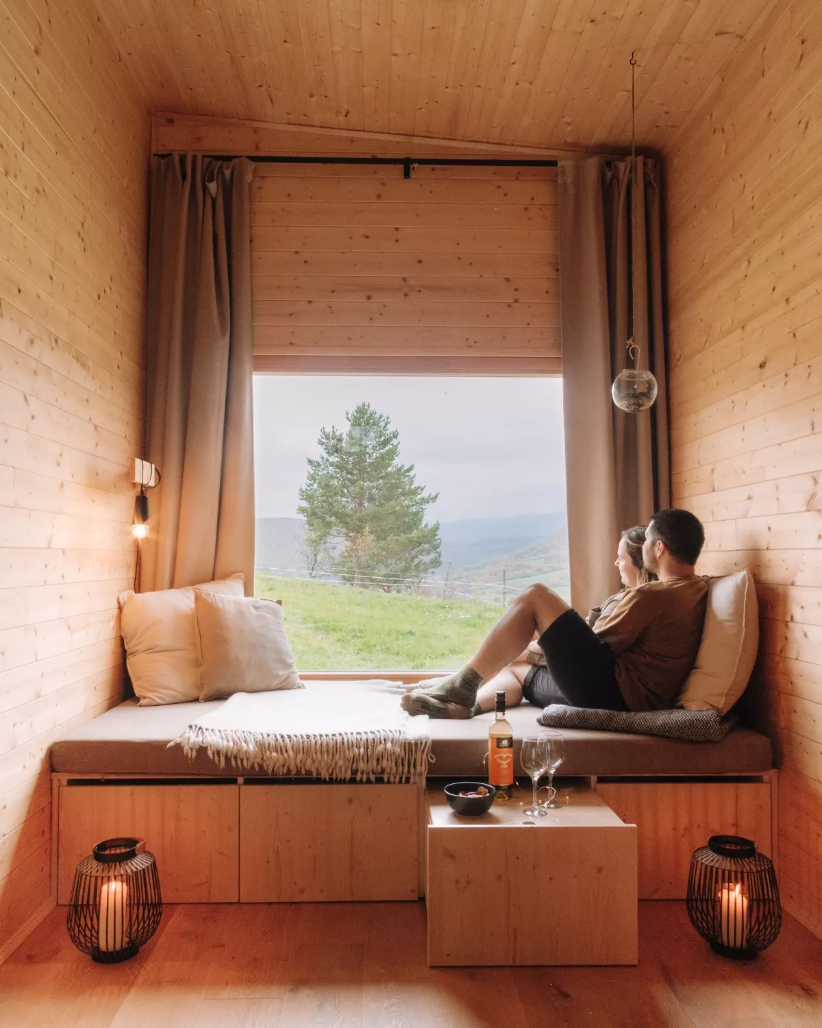 kiva cabins netradicne ubytovanie zamilovany parik pozerajuci sa na vyhlad z postele 